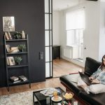 A woman working remotely on a laptop in a cozy, modern living room with snacks on the table.